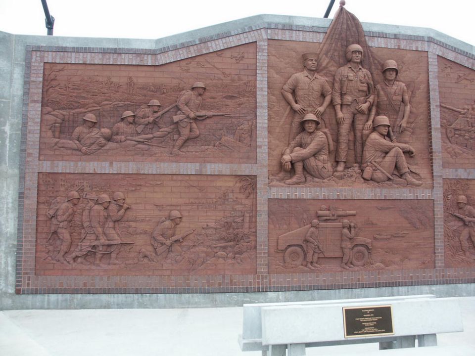 Brick mural depicting soldiers in battle and a military vehicle