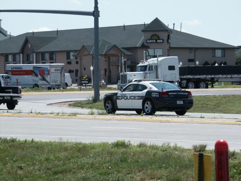 2001 Mercury Grand Marquis - A police car is parked in front of a Days Inn, with a U-Haul truck and semi-trucks in the background.