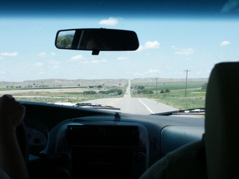 2001 Mercury Grand Marquis - View from inside a vehicle on a long, straight road through a rural landscape under a cloudy sky.