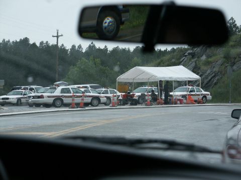 2001 Mercury Grand Marquis - A row of police cars are parked in a lot, some under a tent, with traffic cones visible.
