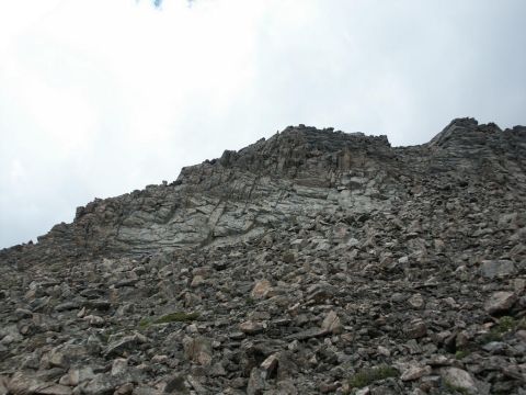 2001 Mercury Grand Marquis - A steep, rocky mountainside with visible geological layers under an overcast sky.