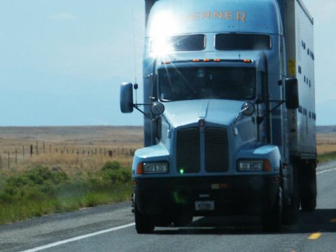 2001 Mercury Grand Marquis - A blue semi-truck travels down a highway under a bright sun, with a trailer attached.