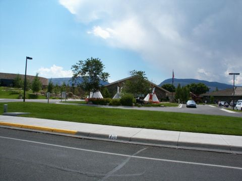 2001 Mercury Grand Marquis - A blue sedan drives past a building decorated with teepees under a cloudy sky.
