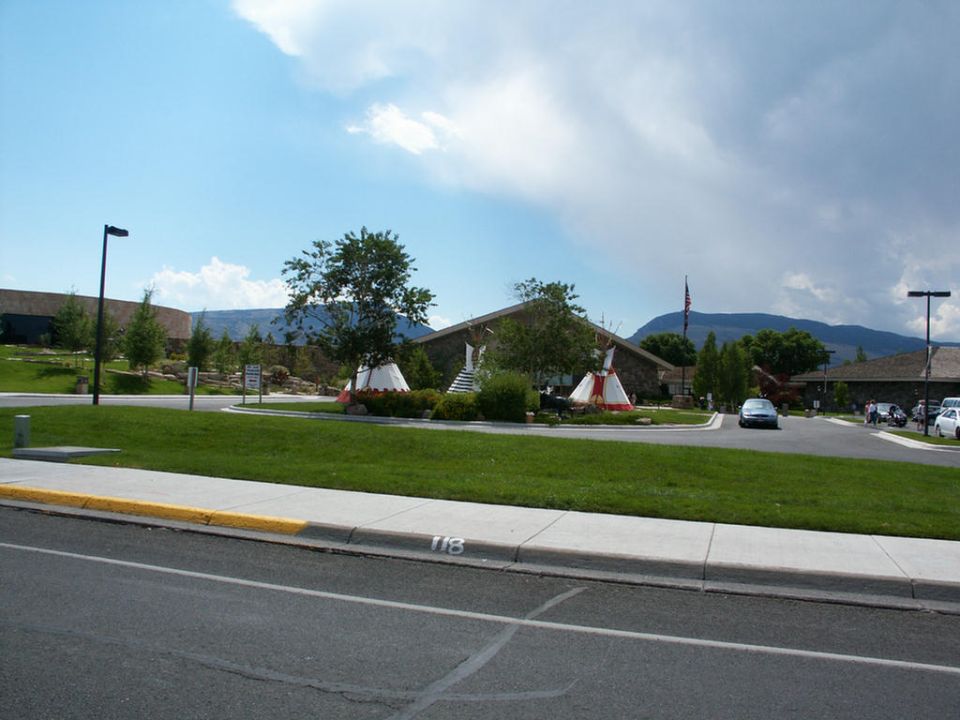 Blue sedan driving past teepees at a roadside attraction