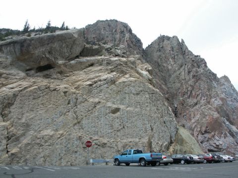 2001 Mercury Grand Marquis - A blue pickup truck is parked in a lot next to a large rock formation, with several other vehicles visible.