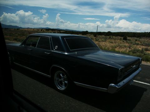 2001 Mercury Grand Marquis - A classic sedan cruises down the road under a cloudy sky.