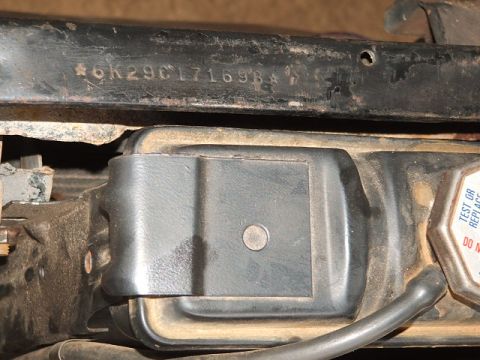 1966 Ford Ranchero - Close-up of a stamped VIN on a black painted radiator support / body brace reading '6K29C171698', with the raised lettering standing out ag…