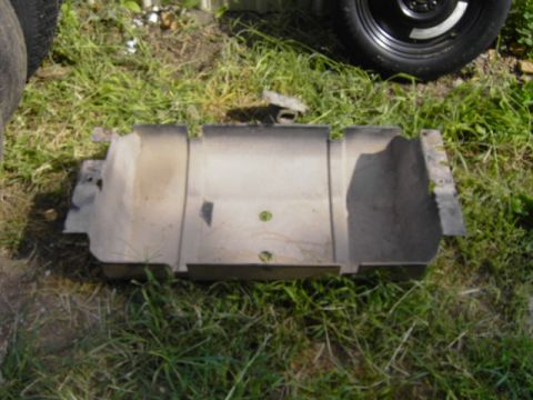 1995 Jeep YJ - A metal component, possibly from a vehicle's undercarriage, rests on a grassy surface next to a tire.