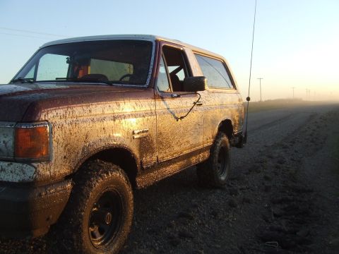 1990 Ford Bronco - Muddy 1990 Ford Bronco on a dirt road during sunrise.