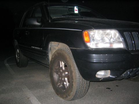 2005 Ford F-250 - A black Jeep Grand Cherokee is parked at night, showing its front right side and wheel.