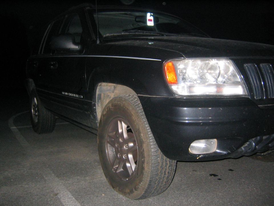 Black Jeep Grand Cherokee, front quarter view. Has a white tag hanging from the rearview mirror