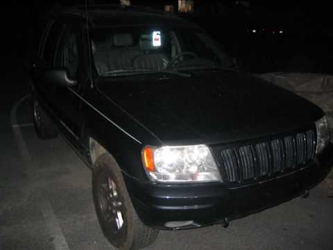 2005 Ford F-250 - A black Jeep Grand Cherokee is parked at night, viewed from the front-three-quarter angle.