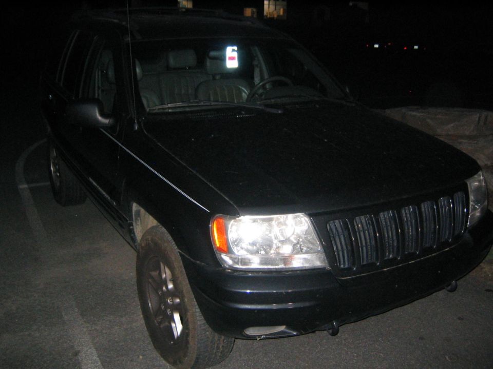 Black Jeep Grand Cherokee with a vertical white and red tag hanging from the rearview mirror