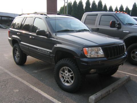 2005 Ford F-250 - This dark Jeep Grand Cherokee is parked next to a Ford pickup truck. The registry claims it is a 2005 Ford F-250, but it is clearly a Jeep.