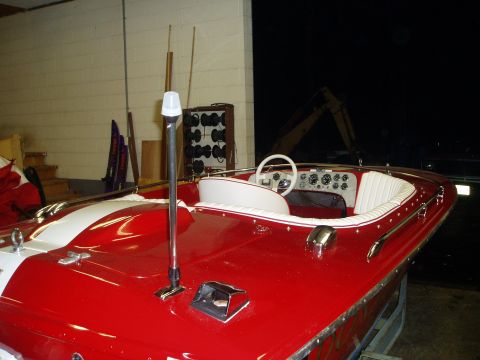 1978 Ford F-250 - A red and white boat is parked indoors, showing its interior with a white steering wheel and upholstered seats.