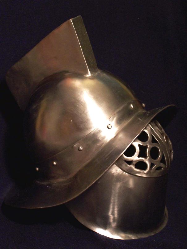 Polished steel crested gladiator helmet with perforated faceplate on blue backdrop