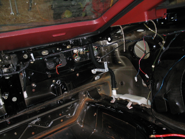 Stripped rear interior of maroon Ford Probe showing bare metal, wiring, and speaker hole during restoration