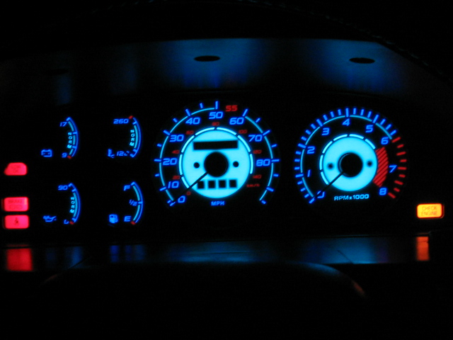 Illuminated instrument cluster with blue gauge faces, red needles, glowing speedometer and tach