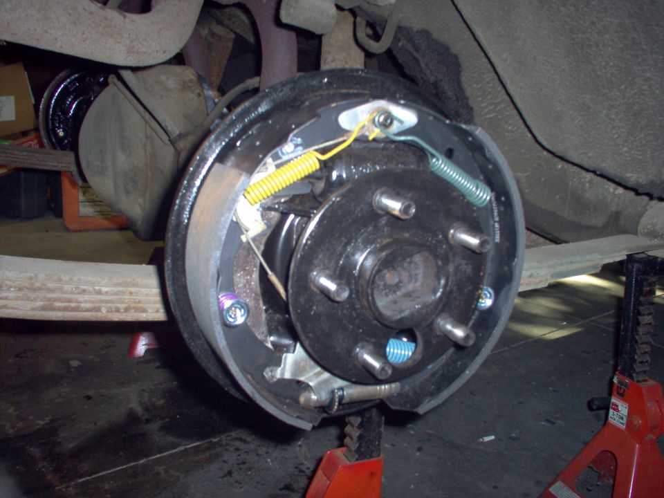 Rear drum brake assembly with new shoes and springs, vehicle supported by jack stands