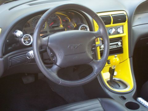 2002 Ford Mustang - Interior view of a car, showing the dashboard, steering wheel, and center console with yellow accents.