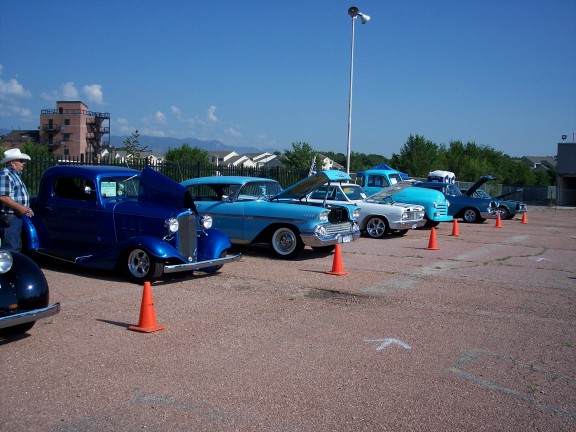 Blue hot rod coupe with hood up, parked at an outdoor car show