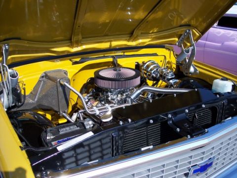 1972 Ford Ranchero - The engine bay of a yellow vehicle, with a purple car visible in the background, suggests a 1970s model.