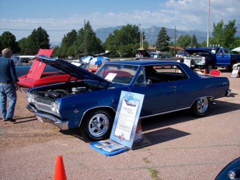 1972 Ford Ranchero - A blue 1966 coupe is displayed with its hood open at a car show, alongside other vehicles and a mountain range in the background.