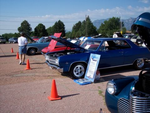 1972 Ford Ranchero - A blue coupe is displayed at a car show with its hood open, alongside other vehicles and attendees.