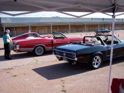 1972 Ford Ranchero - A black convertible Mustang is parked next to a red convertible car.