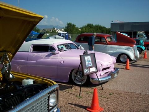 1972 Ford Ranchero - A custom pink coupe with flame decals and a white roof is displayed at a car show next to other classic vehicles.