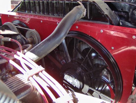 1978 Ford Bronco - Close-up of an engine bay looking down at a black flex-blade cooling fan and clutch mounted ahead of the radiator, with the upper radiator…