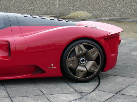 1991 Ford Probe - Close-up of the rear quarter of a red mid-engined exotic with Pininfarina script on the fender, a matte bronze five-spoke wheel, and louver…
