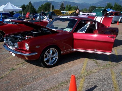 1972 Ford Ranchero - 1965 Ford Mustang fastback on display at a car show with other vehicles present.