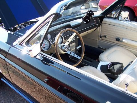 1972 Ford Ranchero - The interior of a black convertible is visible, a wooden steering wheel and fuzzy dice hanging from the rearview mirror.