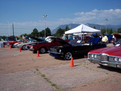 1972 Ford Ranchero - A black convertible with its hood open is displayed at an outdoor car show, with other vehicles and a tent in the background.