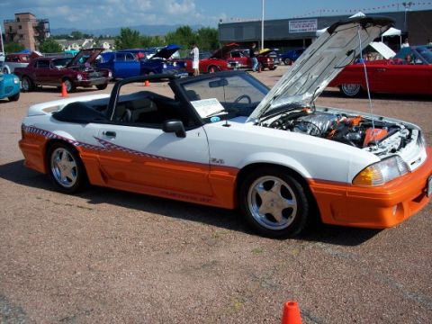 1972 Ford Ranchero - White and orange 1990 Ford Mustang GT convertible at a car show with the hood up.