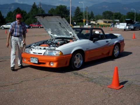 1972 Ford Ranchero - A man stands by a white and orange convertible with its hood open, parked outdoors.
