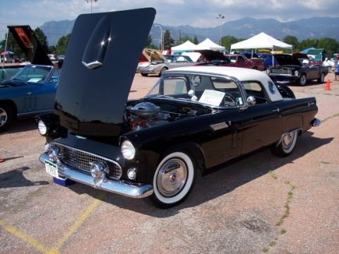1972 Ford Ranchero - A black 1955 Ford Thunderbird is displayed with its hood open at an outdoor car show. Other vehicles and tents are visible in the backgroun…