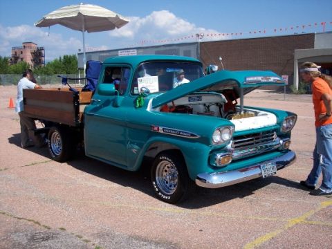 1972 Ford Ranchero - A teal 1959 Chevrolet Apache pickup truck is displayed with its hood open at an outdoor event.
