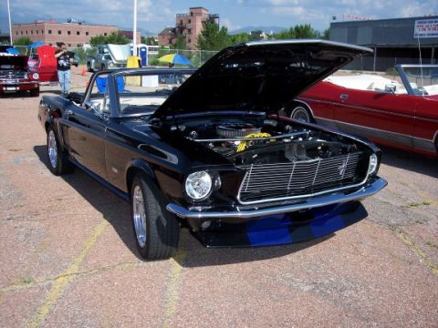 1972 Ford Ranchero - Black 1967 Ford Mustang convertible on display with hood open, another convertible visible to the right.