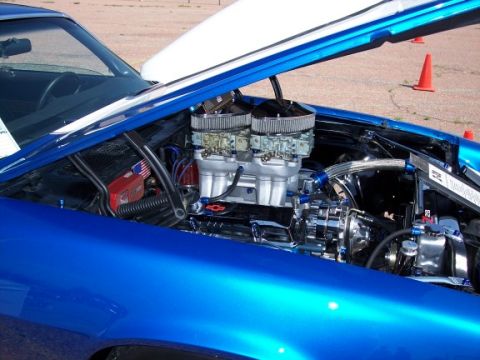 1972 Ford Ranchero - The engine bay of a blue car is visible with the hood open, revealing a custom engine setup.