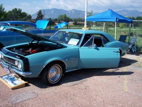 1972 Ford Ranchero - A turquoise 1967 Chevrolet Camaro is displayed with its hood and door open, next to another blue car.