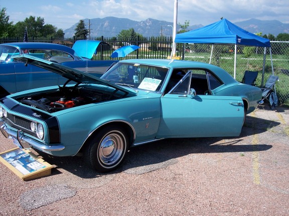 Turquoise 1967 Chevrolet Camaro coupe with hood and driver door open, parked outdoors