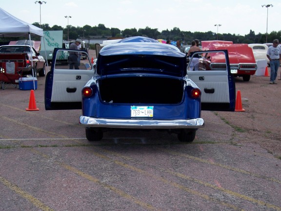 Blue 1950s car with open doors and trunk, rear view. License plate reads 7G9-LHH