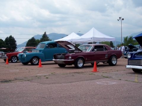 1972 Ford Ranchero - A maroon 1967 Ford Mustang coupe is displayed with its hood open at an outdoor car show, alongside other classic vehicles.