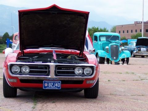 1972 Ford Ranchero - A red 1969 Pontiac Firebird is displayed with its hood open, alongside other vehicles at an outdoor event.