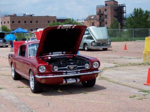 1972 Ford Ranchero - A red 1965 Ford Mustang is parked with its hood up, alongside another vehicle in the background.