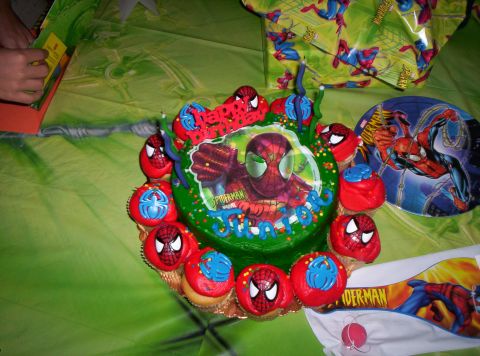 1986 Ford Bronco - A Spiderman-themed birthday cake and cupcakes are displayed on a green tablecloth, with Spiderman wrapping paper in the background.