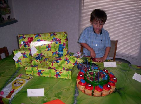 1986 Ford Bronco - A young boy stands by a table set for a birthday party, a Spiderman cake and wrapped gifts.