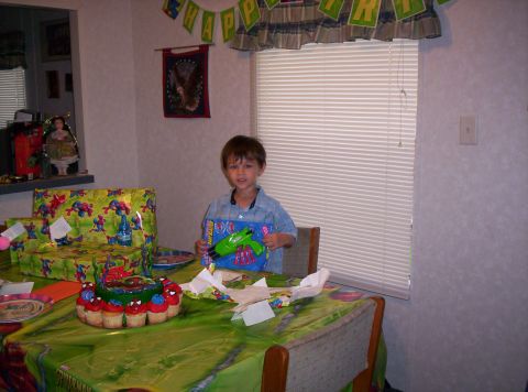 1986 Ford Bronco - A young boy sits at a table laden with birthday gifts and a cake, holding a new toy.